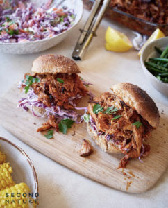 bbq pulled pork inside bread buns with red cabbage coleslaw on a wooden platter