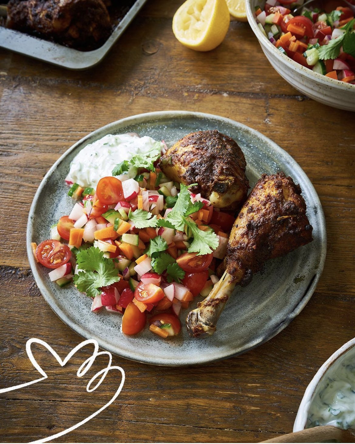 two tandoori chicken drumsticks with a kachumber salad and tzatziki 